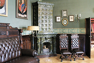 Image of a green room, with dark brown, leather seating and a portrait paintings on the wall